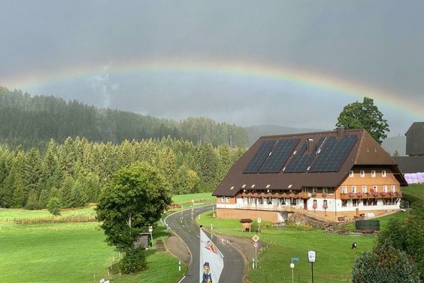 Ein Regenbogen liegt berm Hof